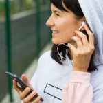 A Caucasian woman uses a smartphone via wired headphones with a headset