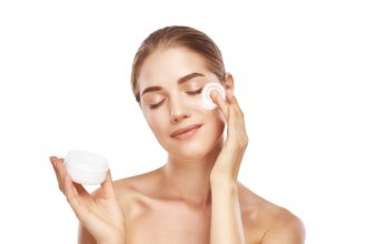 Anti-Ageing Products. Portrait of healthy young woman with closed eyes applying moisturizer cream on