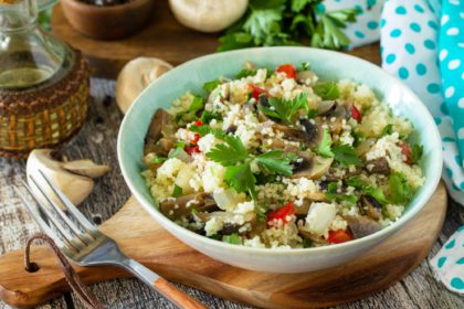 Diet food vegan concept. Vegan salad with couscous and champignons on a wooden table.