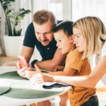 Happy family with son using mobile apps together at home