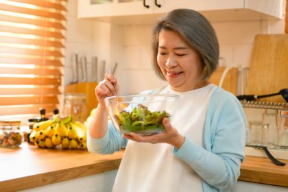 mature and old adult woman takes on the role of a skilled cooking salad.