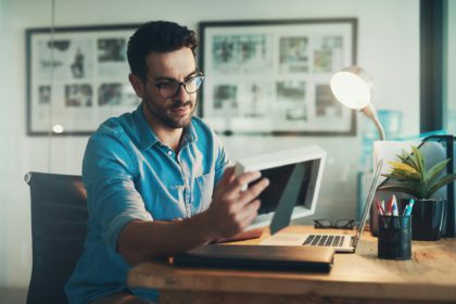 Shot of a young businessman looking at a photo frame while working in his office