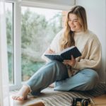 Young beautiful female student at home doing creative journal.