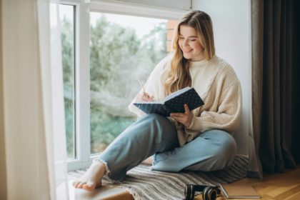 Young beautiful female student at home doing creative journal.